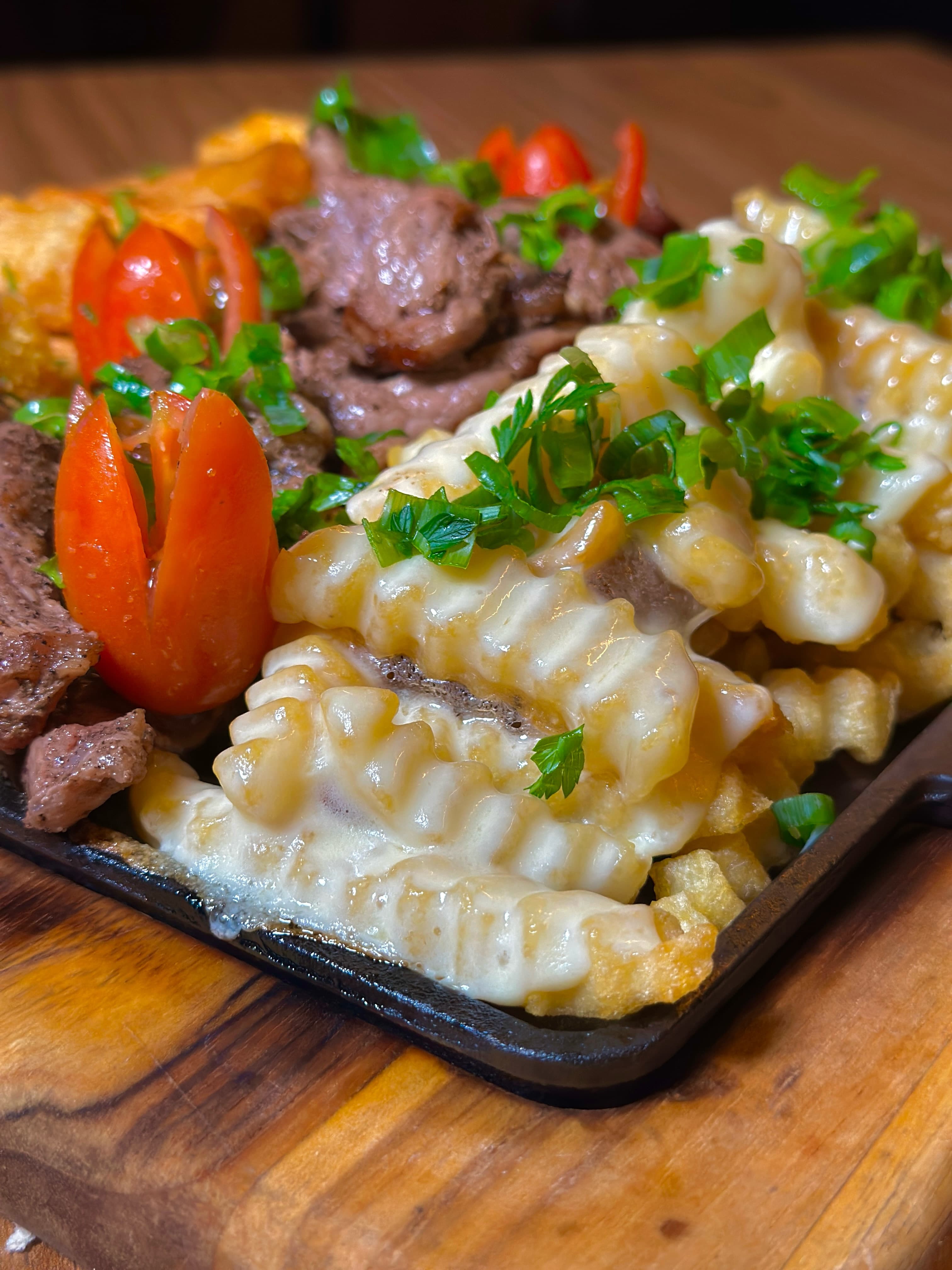 Porção Mix de perto: iscas de ancho, mandioca, batata crinkle e queijo gratinado