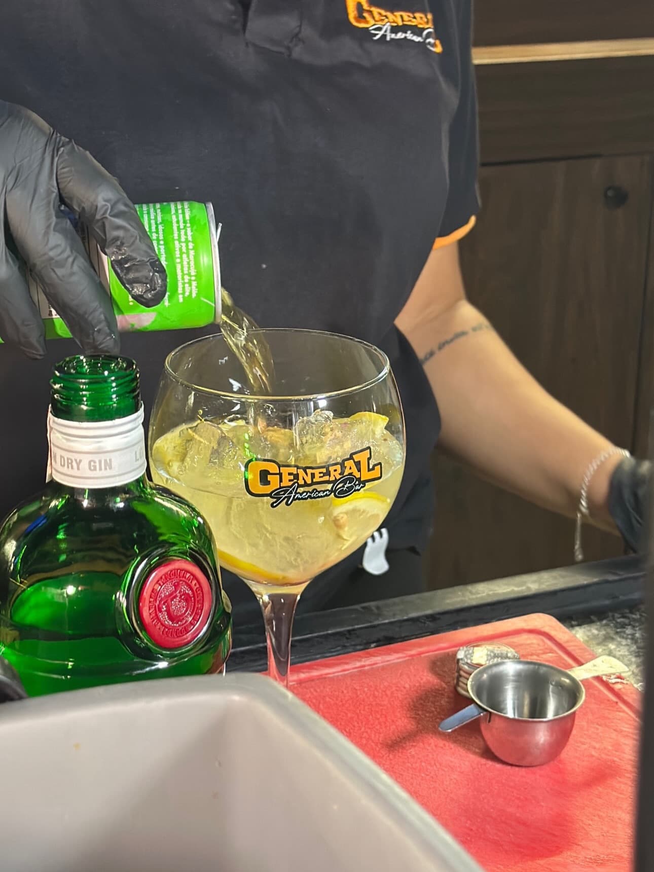 Bartender preparando um gin tônica na taça com o logo do General