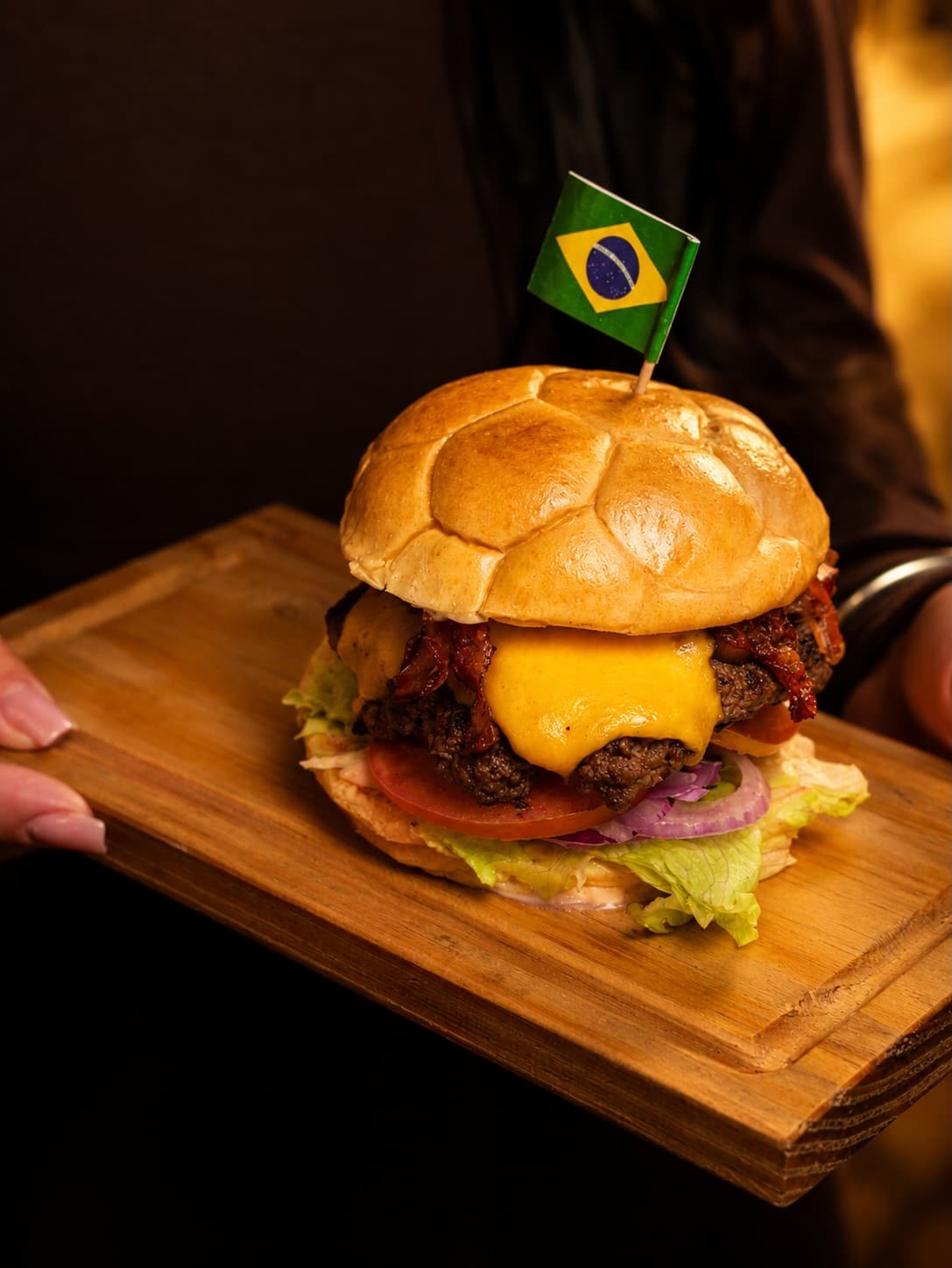Burger artesanal com cheddar e bacon numa tábua de madeira